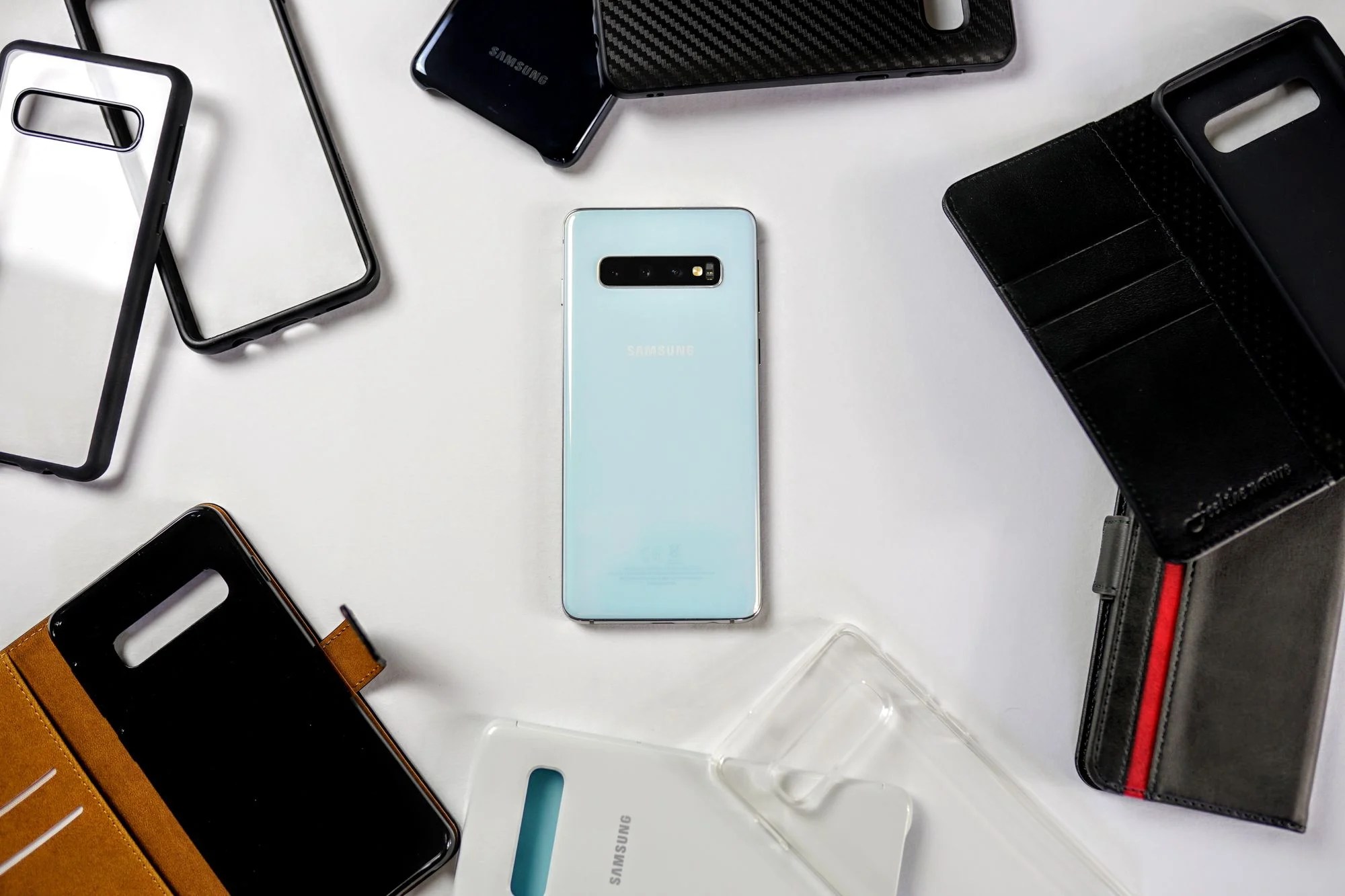 Un Samsung Galaxy S10 au milieu de nombreuses coques et protections de smartphone.