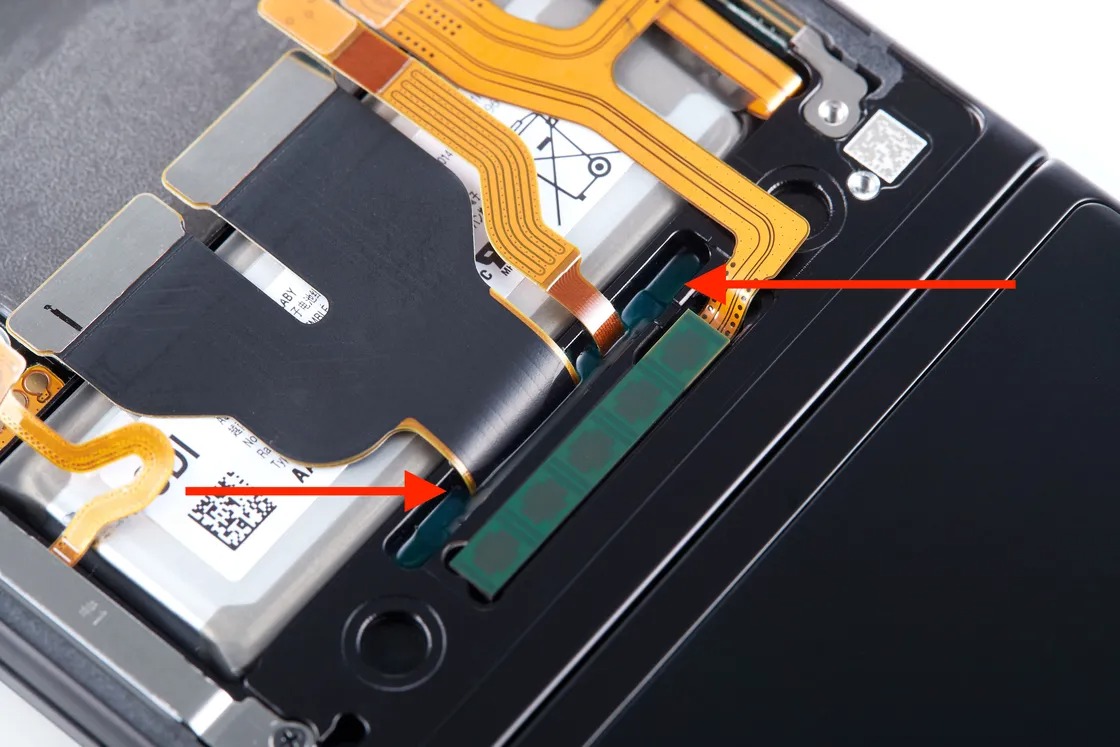 Un joint durci sur place pour l&rsquo;étanchéité à l&rsquo;eau sur un Galaxy Z Flip 3. Il est injecté sous forme liquide en usine, puis durci pour créer un joint flexible autour du ruban de câble.