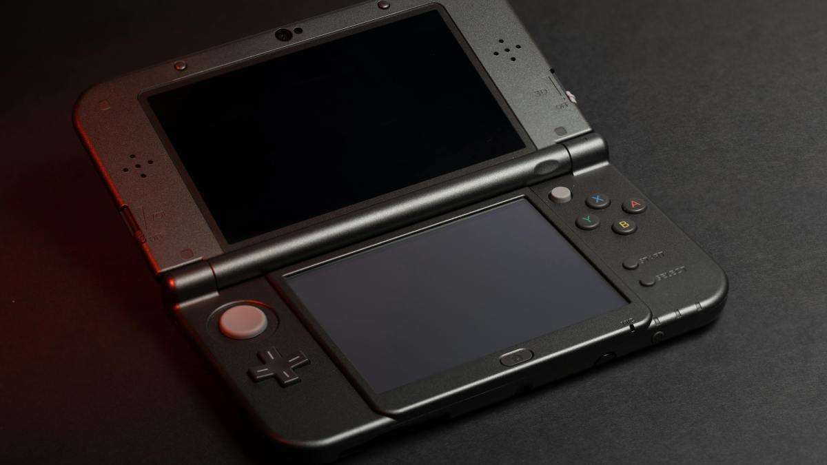 Une Nintendo 3DS XL noire sur un tapis de bureau noir