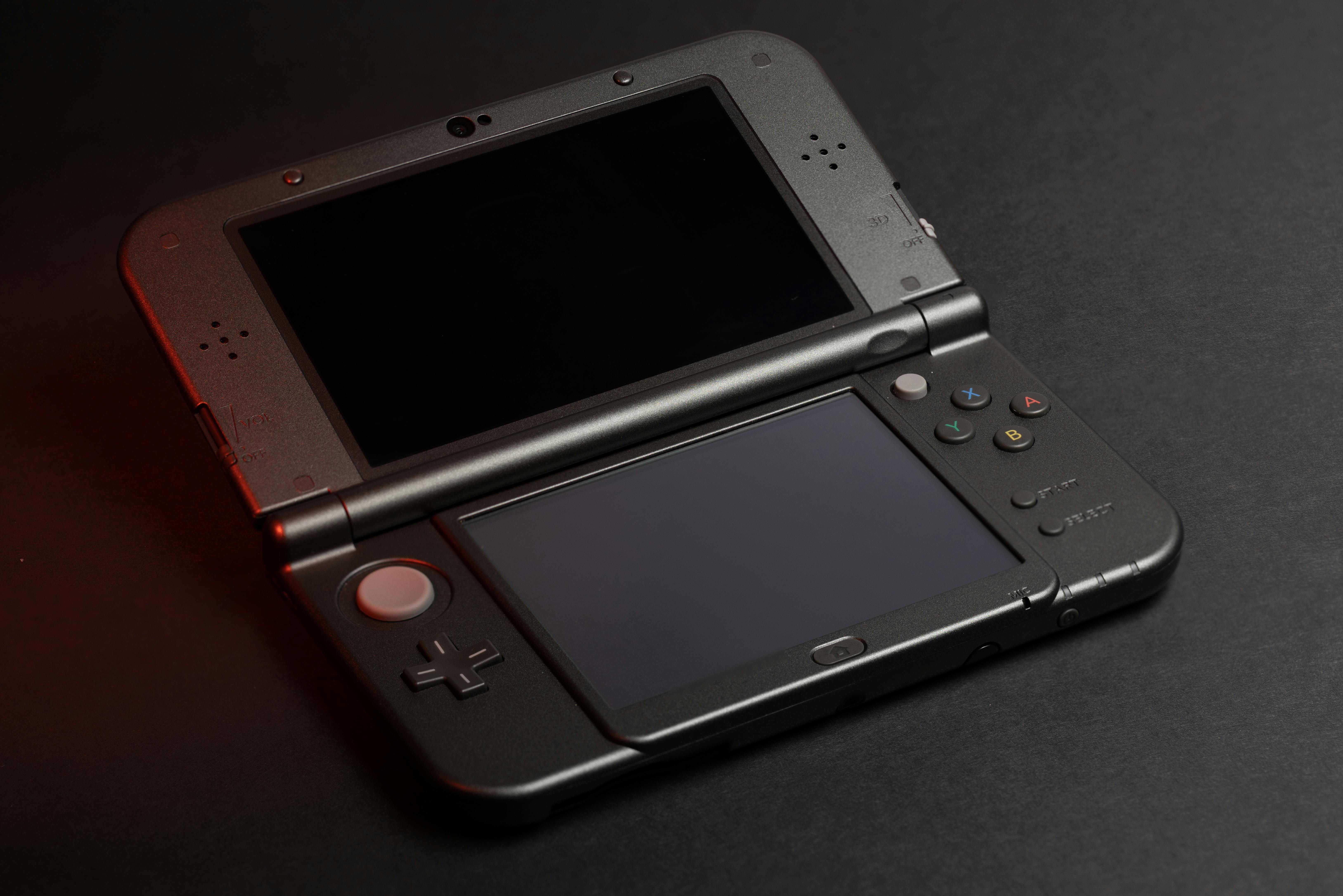 Une Nintendo 3DS XL noire sur un tapis de bureau noir
