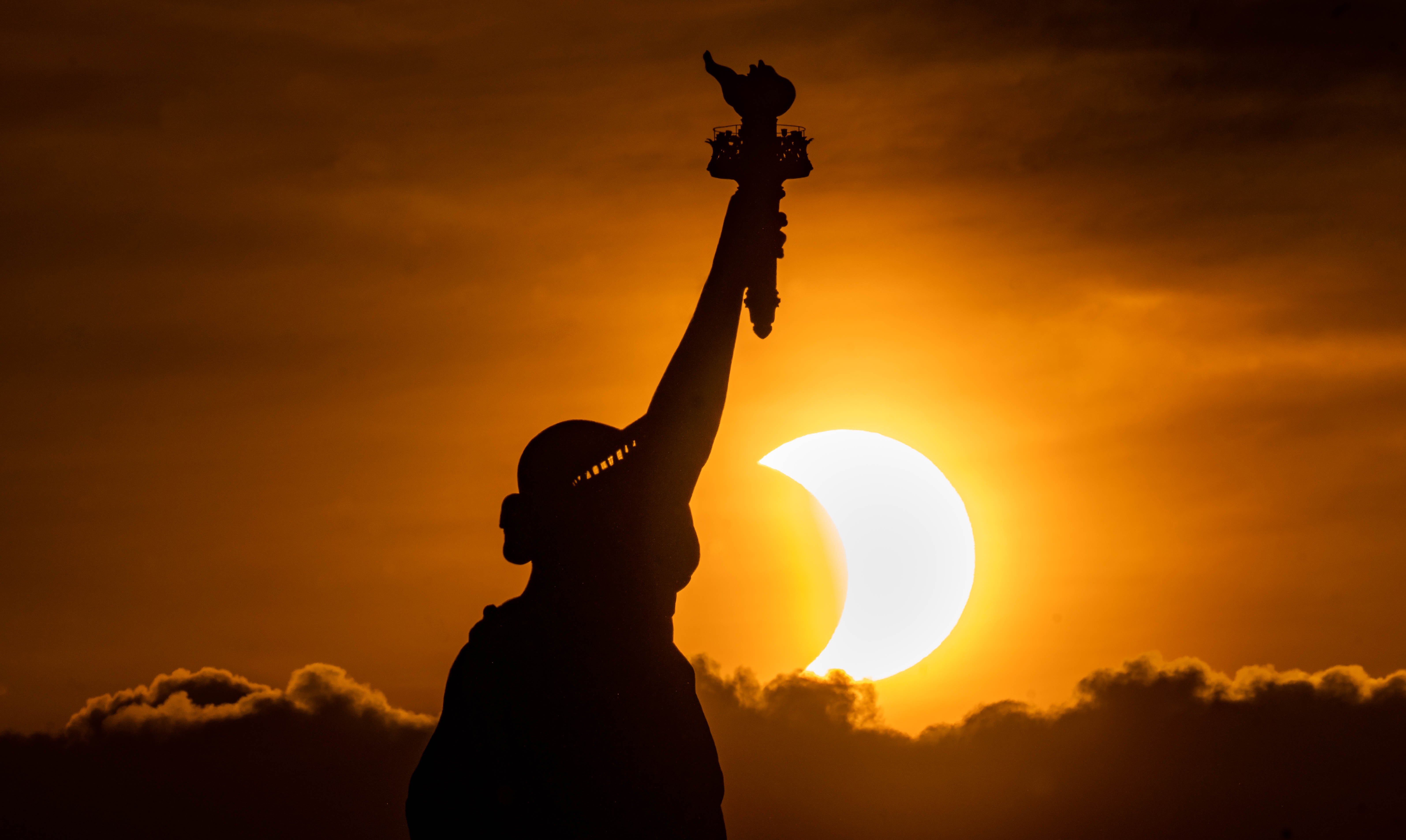 Photo d'éclipse avec la statue de la liberté au premier plan