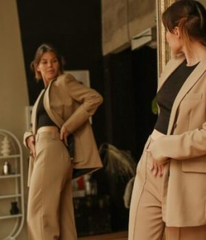 Une jeune femme essaye devant un miroir comment lui va un tailleur pantalon (photo prétexte d'une banque d'image)
