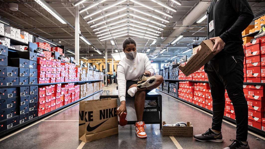 Une femme en train d'essayer des baskets dans une boutique Nike