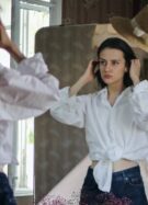 Une jeune femme essaye un jean face à un miroir