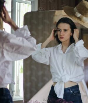 Une jeune femme essaye un jean face à un miroir