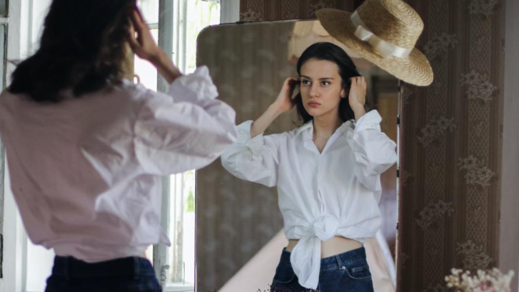 Une jeune femme essaye un jean face à un miroir