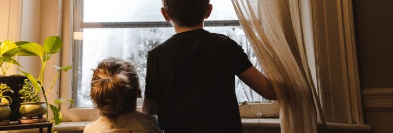 Deux enfants regardent par la fenêtre