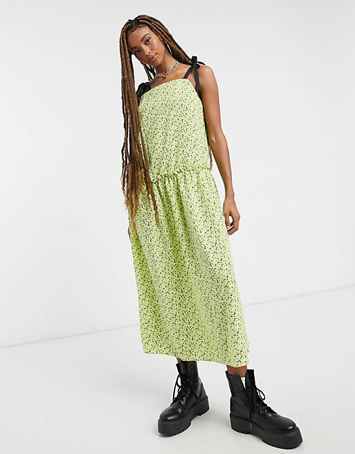 Robe sur fond vert clair imprimée de petites fleurs blanches et feuilles noires, froncée à la taille et contrasté par de fines bretelles en ruban noir à noeuds, Topshop, 28,99€ au lieu de 49,99€.