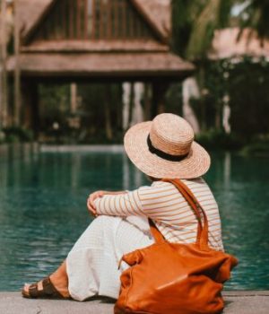 Femme avec un sac 48h à l'épaule, assise devant une piscine