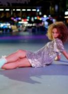 Une femme en patins à roulette et robe à sequins assise au sol
