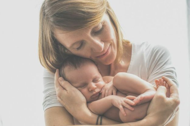 Une femme serre tendrement dans ses bras un petit bébé.