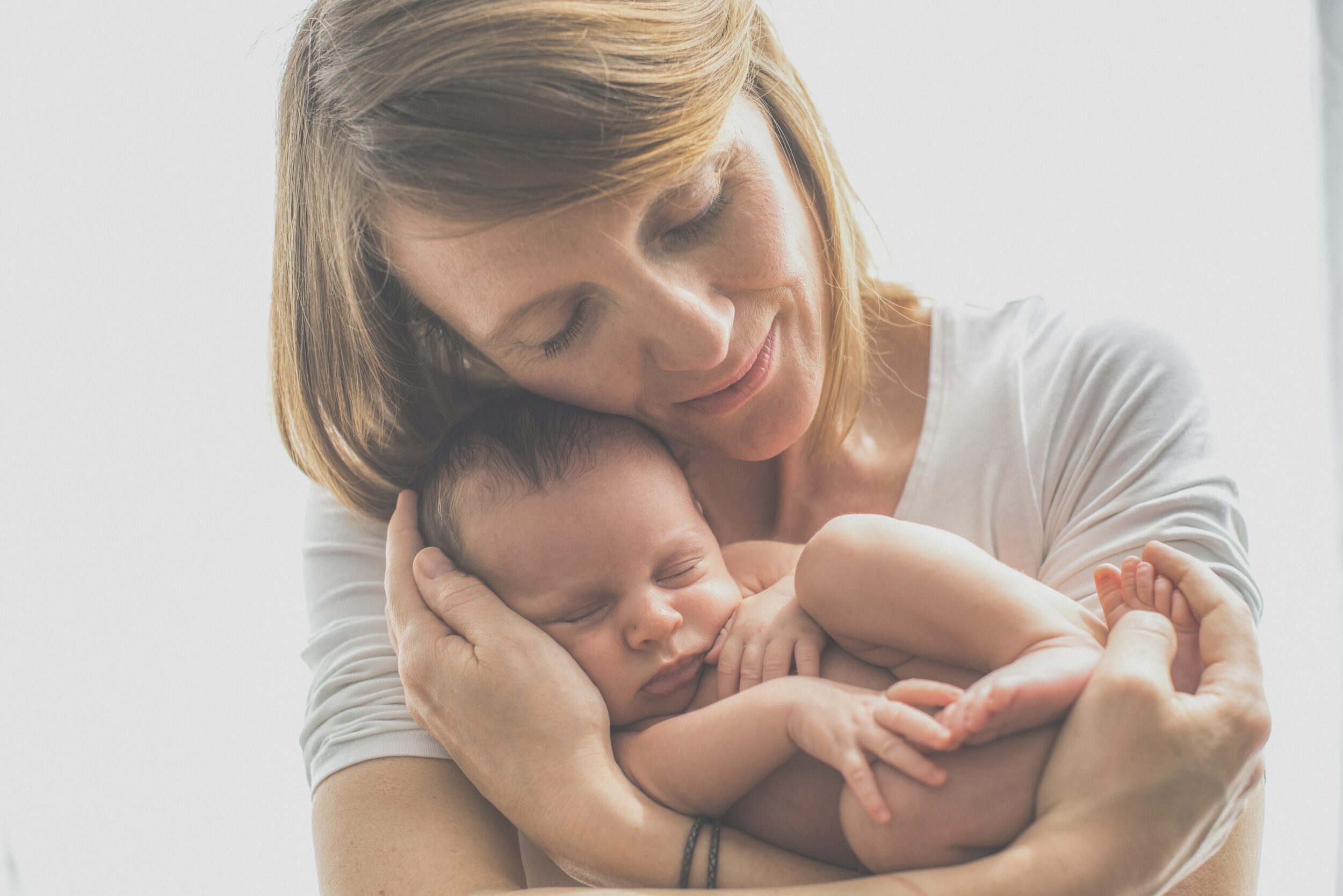 Une femme serre tendrement dans ses bras un petit bébé.