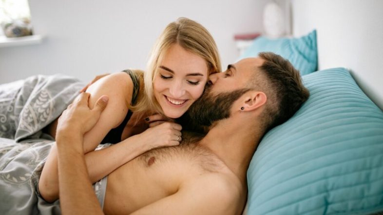 Couple d'un homme et d'une femme allongés dans un lit et souriant
