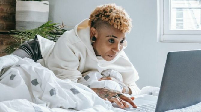 Jeune femme surfant sur internet dans son lit