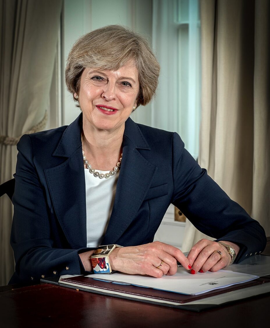 Le portrait officiel de Theresa May, posant à son bureau.
