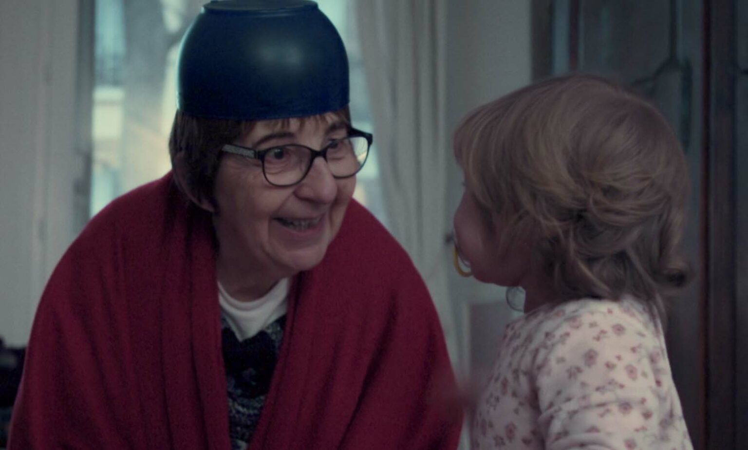 Chantal Birman, un bol sur la tête, fait rire un enfant en bas âge. Chantal Birman, un bol sur la tête, fait rire un enfant en bas âge.