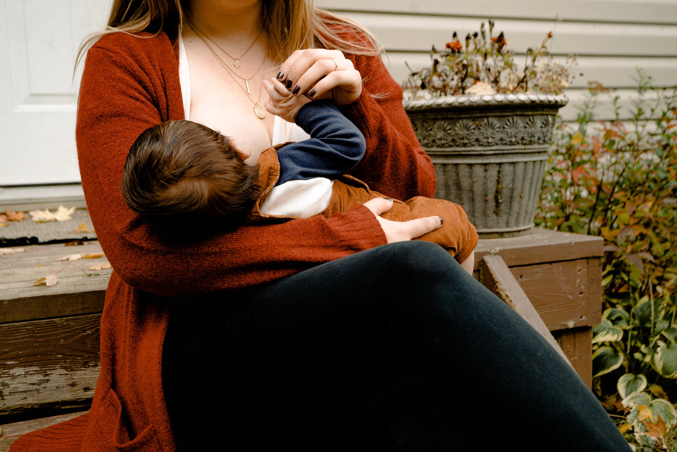 Une femme assise sur un banc, allaitant son enfant.