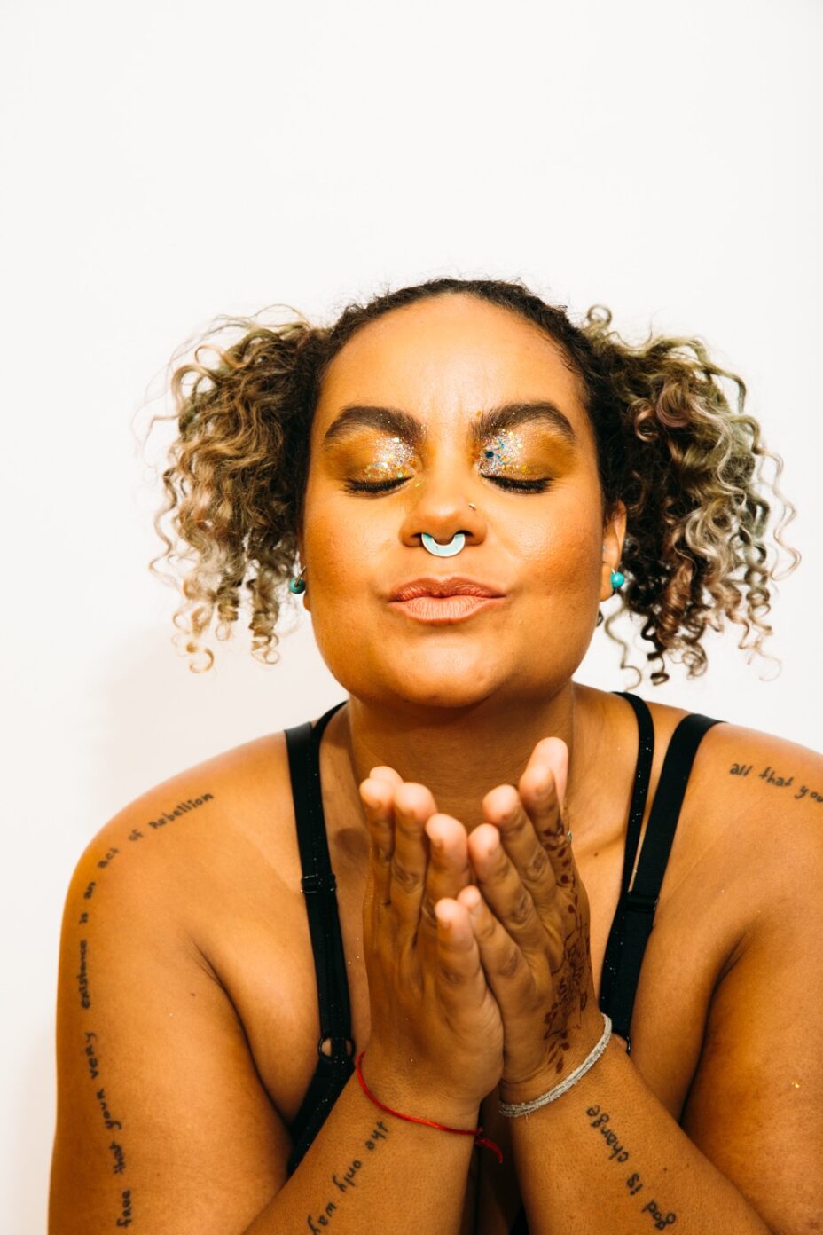 Adrienne Maree Brown, une femme métisse aux paupières pailletées, à l'air serein, aux nombreux tatouages. Adrienne Maree Brown, une femme métisse aux paupières pailletées, à l'air serein, aux nombreux tatouages.