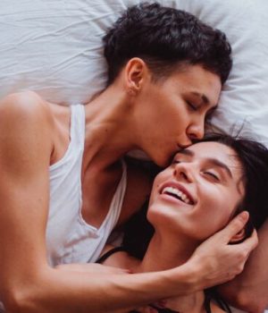 Deux femmes amoureusement enlacées sur un lit.