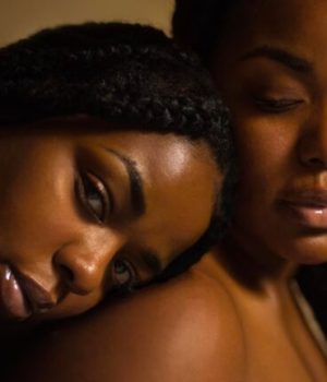 Deux femmes noires, l'une pose sa tête sur l'épaule de l'autre.