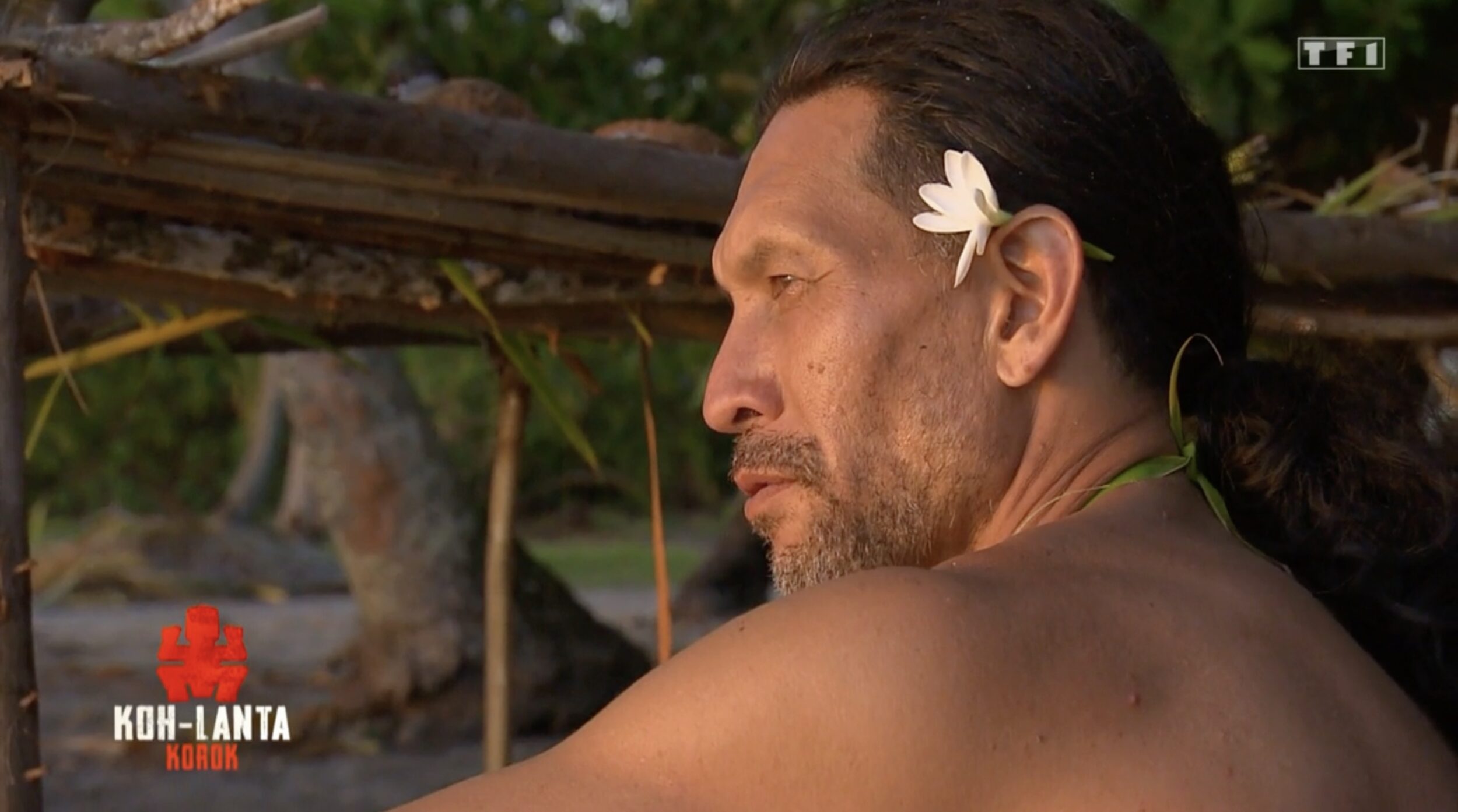 Teheiura est assis sur la plage, une fleur dans les cheveux.