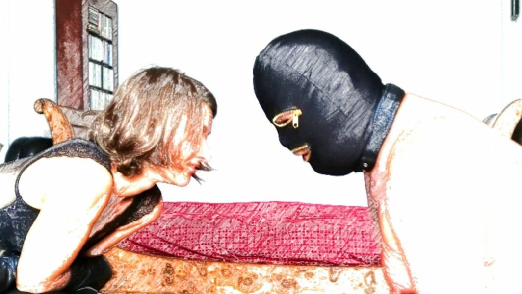 femme en noir face à un homme portant une cagoule BDSM