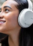 Jeune femme souriante avec le casque bluetooth à réduction de bruit de Sony sur les oreilles 