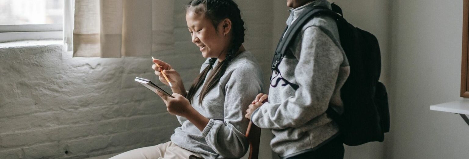 Deux enfants à l'école regardent l'écran d'un smartphone