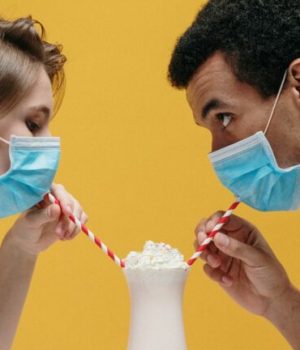 deux personnes en train de boire un verre avec leurs masques