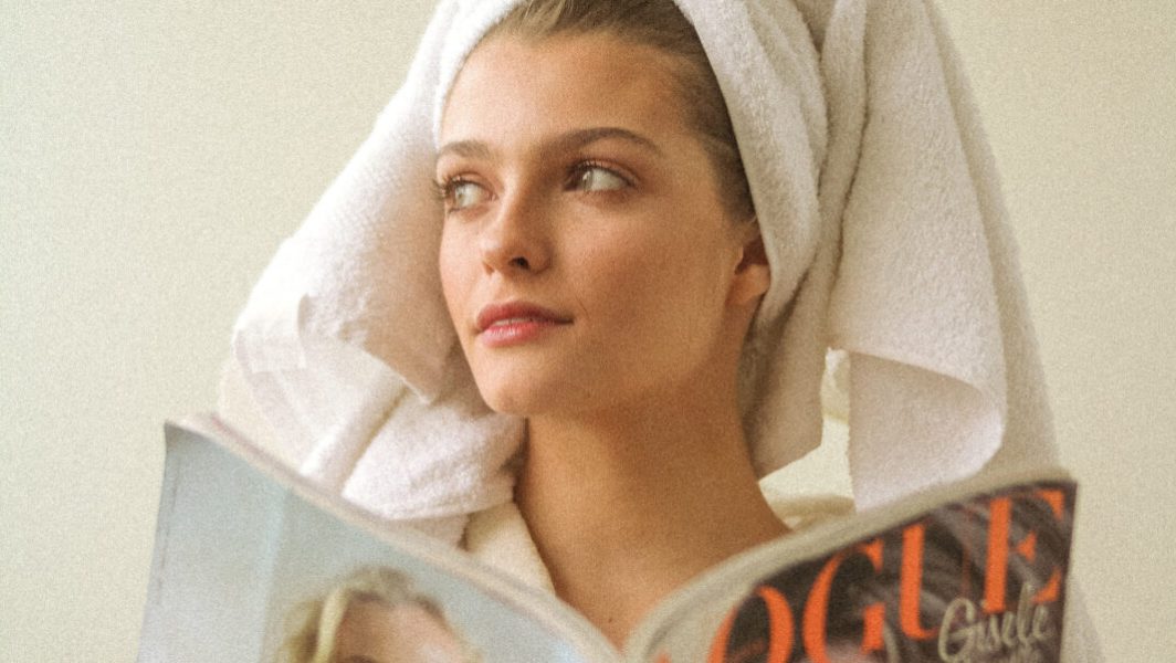 Jeune femme avec une serviette sur la tête lisant un magazine