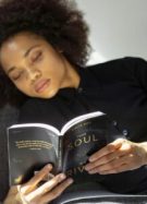 Une jeune femme noire lisant un roman.