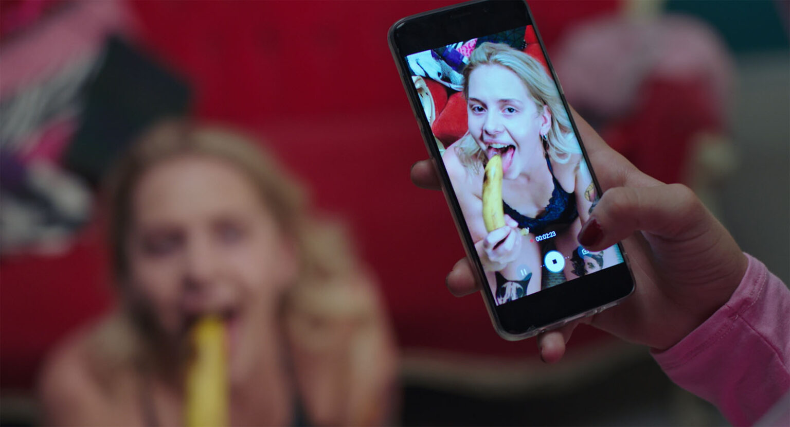 Une jeune femme filmée par un smartphone mime une fellation sur une banane. Une jeune femme filmée par un smartphone mime une fellation sur une banane.