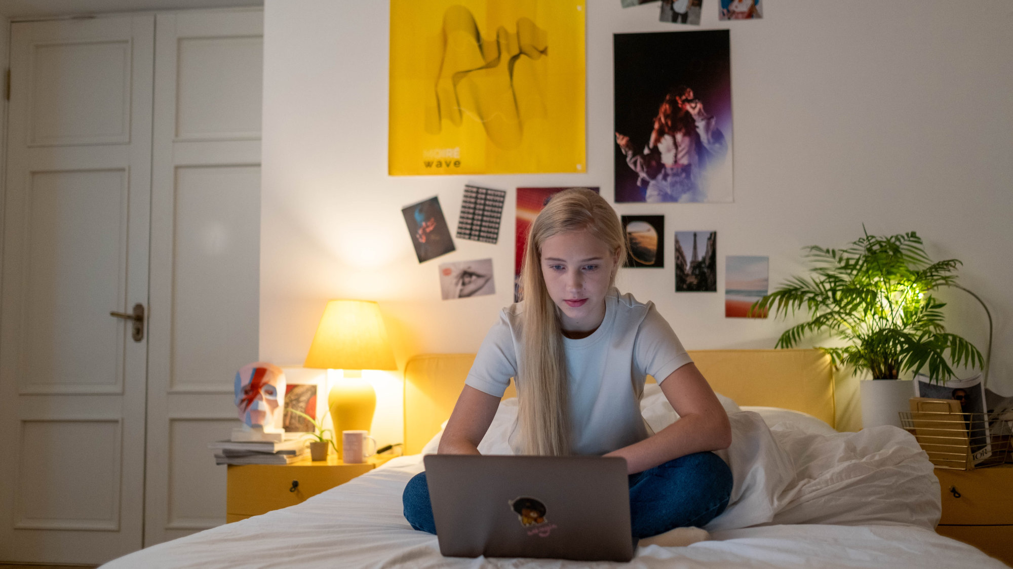 Une adolescente sur un ordinateur, sur son lit.