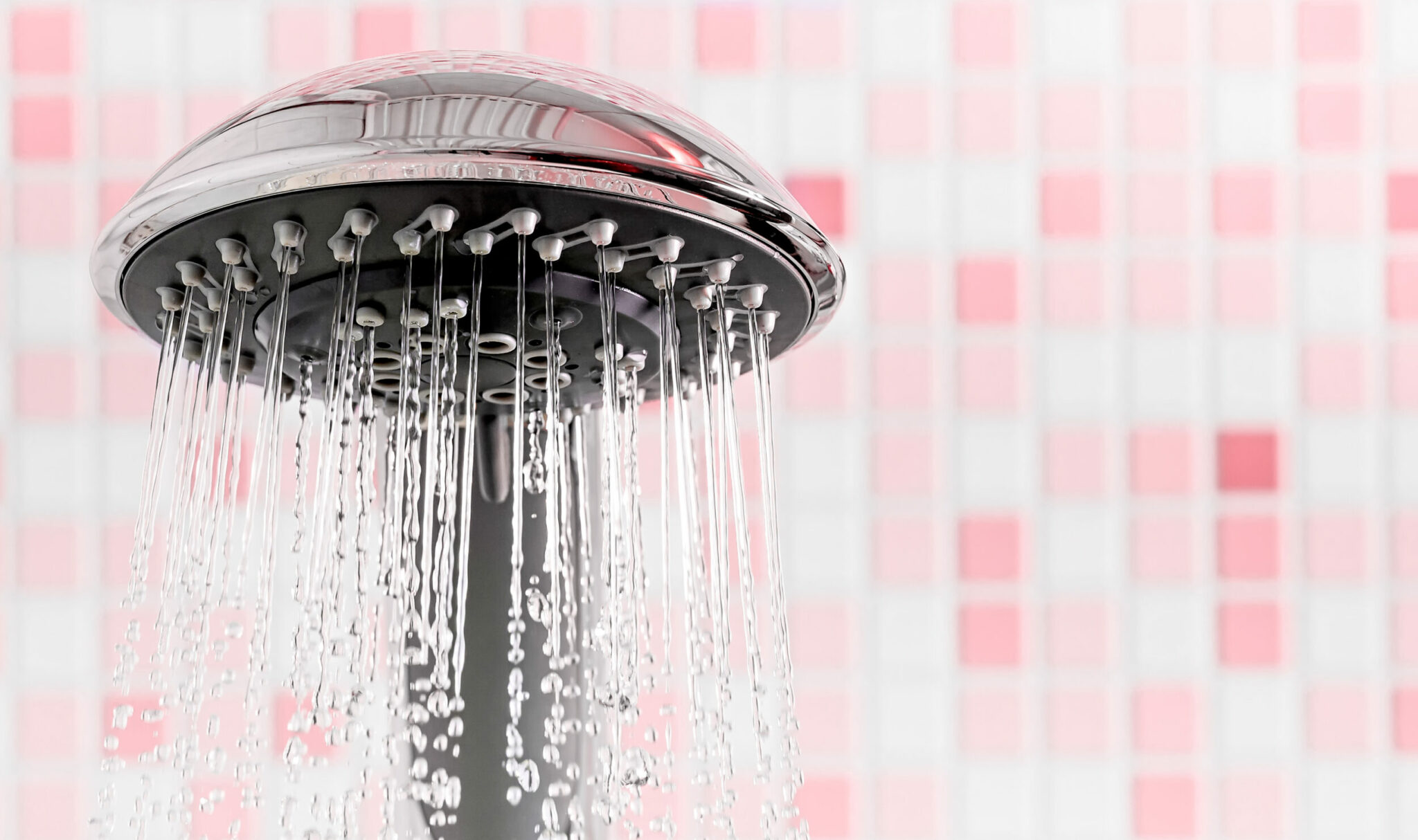 Modern Shower head with running water in pink bathroom. Copy space Modern Shower head with running water in pink bathroom. Copy space