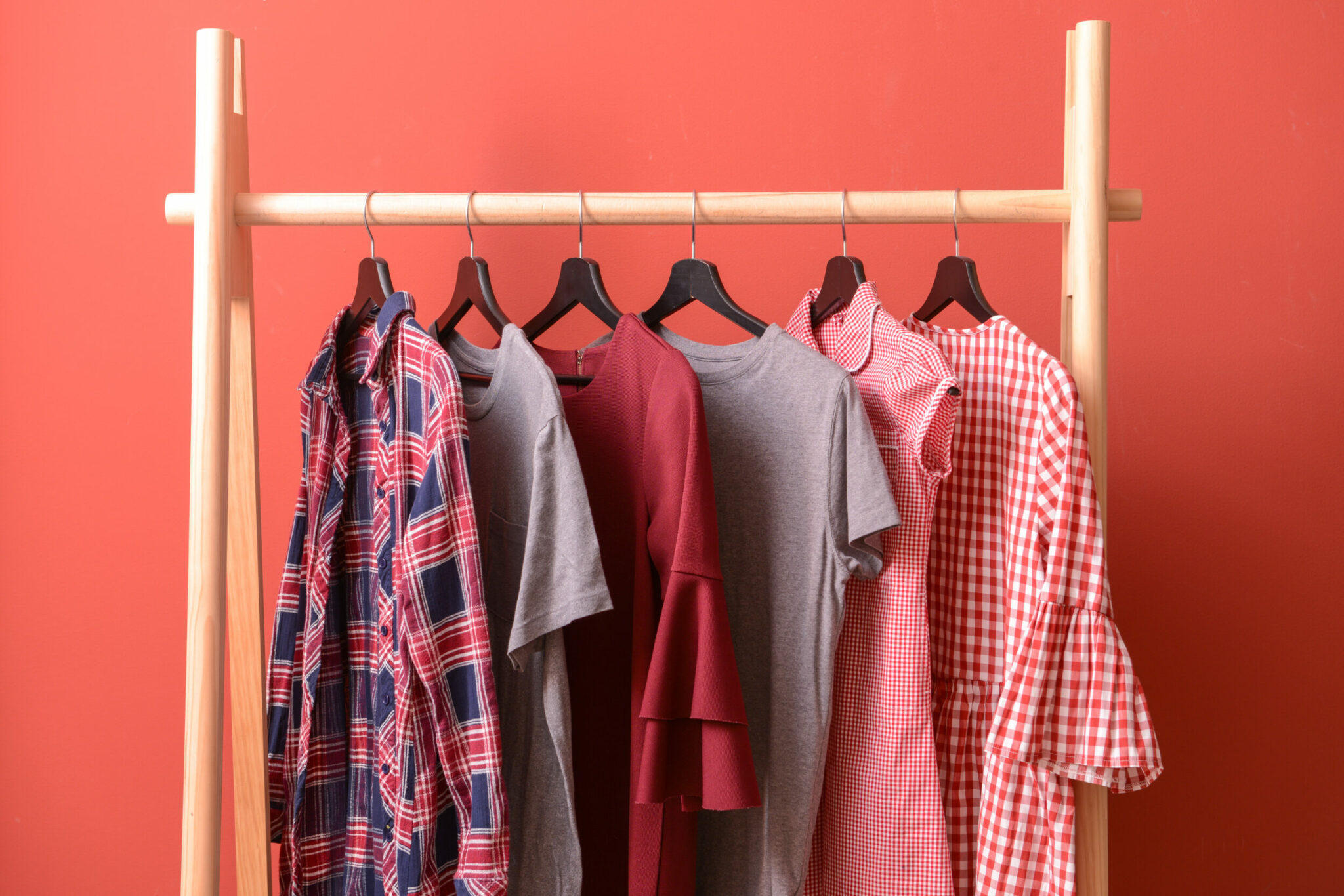 Rack with hanging clothes on color background Rack with hanging clothes on color background