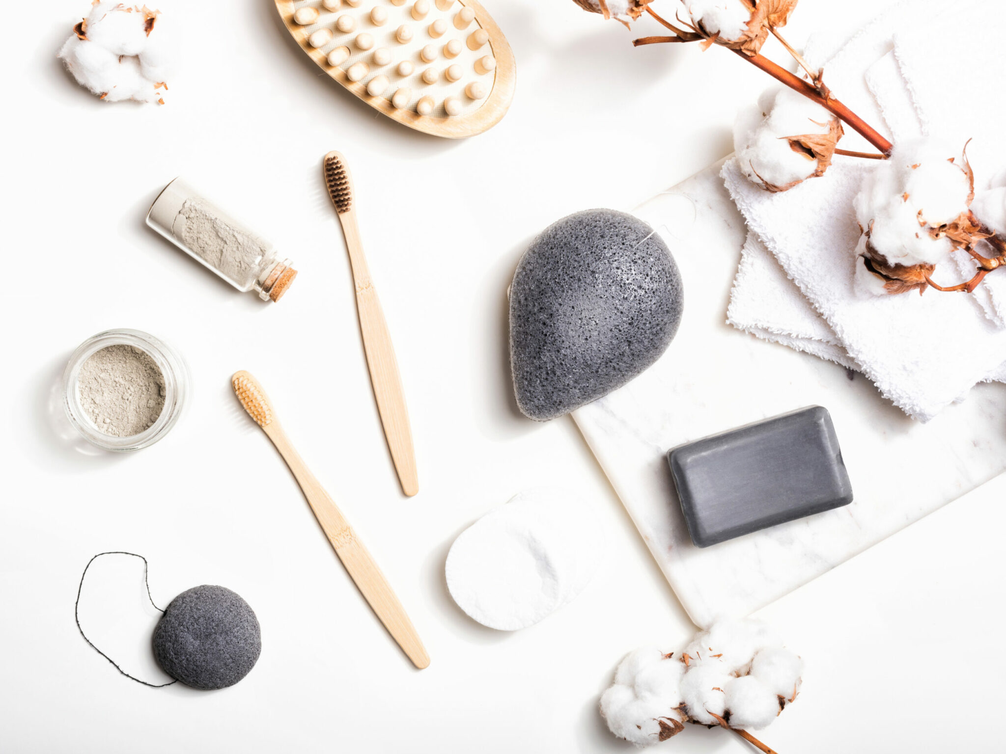 Bathroom natural accessories on white background. Eco bamboo toothbrushes, konjac sponge, clay mask, reusable cotton pads. Plastic free and zero waste concept