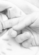 main de bébé autour d'un doigt d'adulte