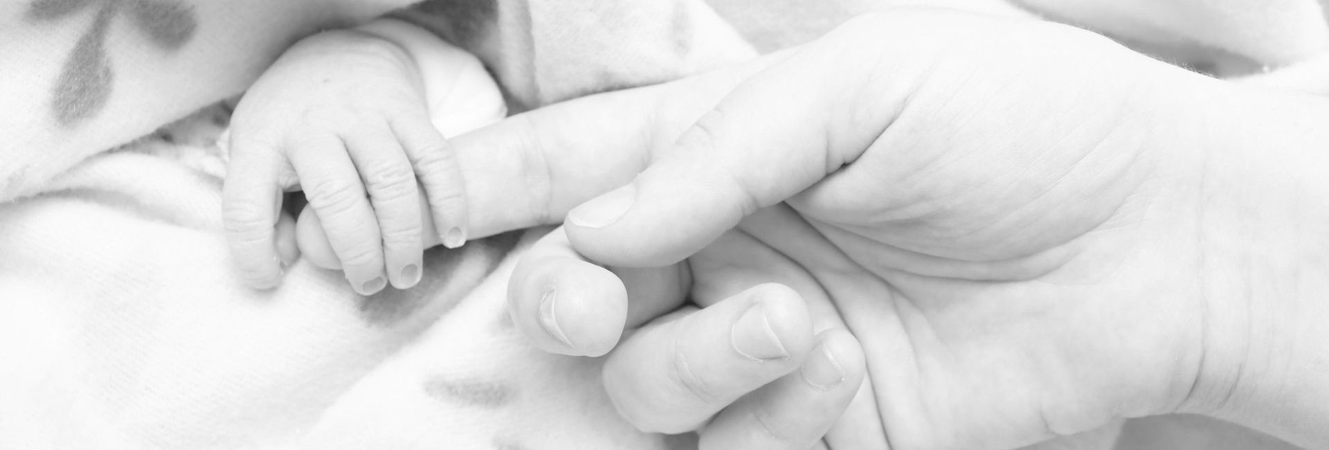 main de bébé autour d'un doigt d'adulte