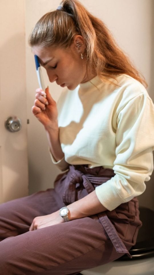 femme assise avec un test de grossesse à la main