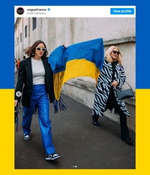 Deux femmes aux abords d'un défilé en train d'agiter un drapeau de l'Ukraine, alors que la Russie vient d'attaquer ce pays.