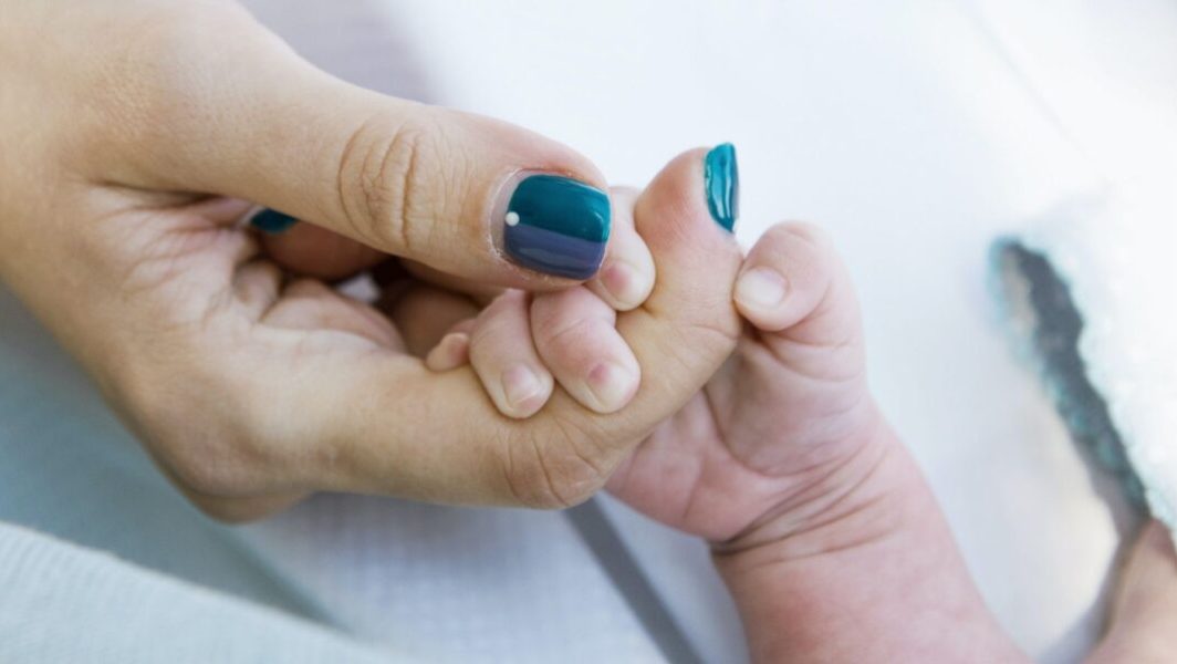 main de bébé tenant un doigt d'adulte