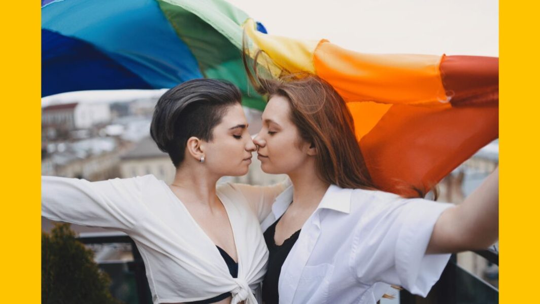 Deux femmes s'embrassent sous un drapeau arc-en-ciel, symbole LGBT © Gustavo Fring de la part de Pexels