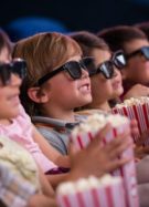 Des enfants en train de regarder un film au cinéma avec du popcorn © Andresr de la part de Getty Images Signature via Canva