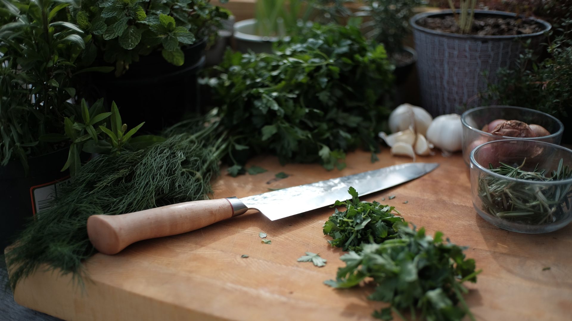 Planche à découper pleine d'herbes, d'aromates avec un couteau posé dessus