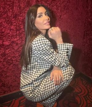 Jenifer accroupie en costume à carreaux noir et blanc // Source : Capture d'écran Instagram Jenifer accroupie en costume à carreaux noir et blanc // Source : Capture d'écran Instagram
