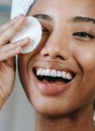 Jeune femme utilisant un disque de coton pour appliquer une lotion hydratante sur son visage. // Source : Sora Shimazaki/Pexels
