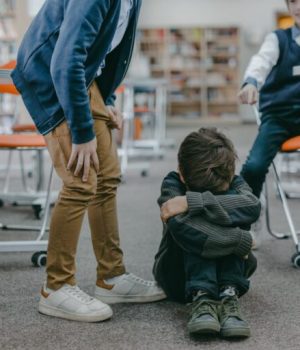 Un enfant victime de harcèlement scolaire, qui pleure assis par terre dans ses genoux // Source : Pexels