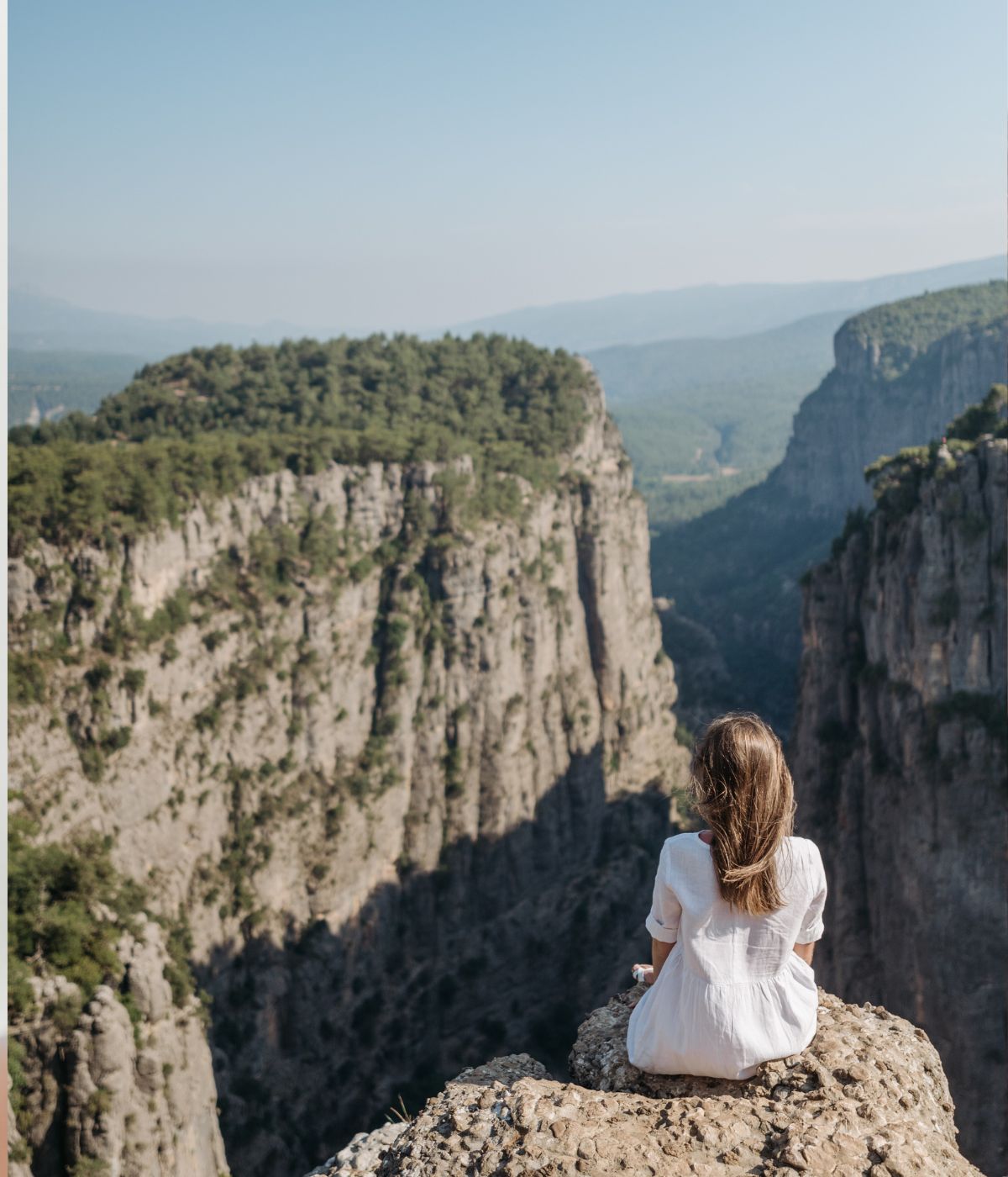 femme de dos face au vide d'une falaise devant un paysage // Source : Photo de Pavel Danilyuk - pexels