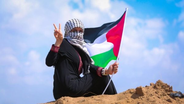 Une femme qui porte un keffieh palestinien sur son visage et le drapeau de la Palestine à la main // Source : hosny_salah de pixabay