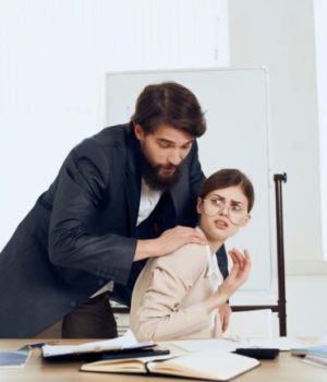 Un homme en train de toucher de façon inappropriée une femme sur son lieu de travail, ce qui peut être considéré comme une forme de violence sexiste // Source : Shotprime